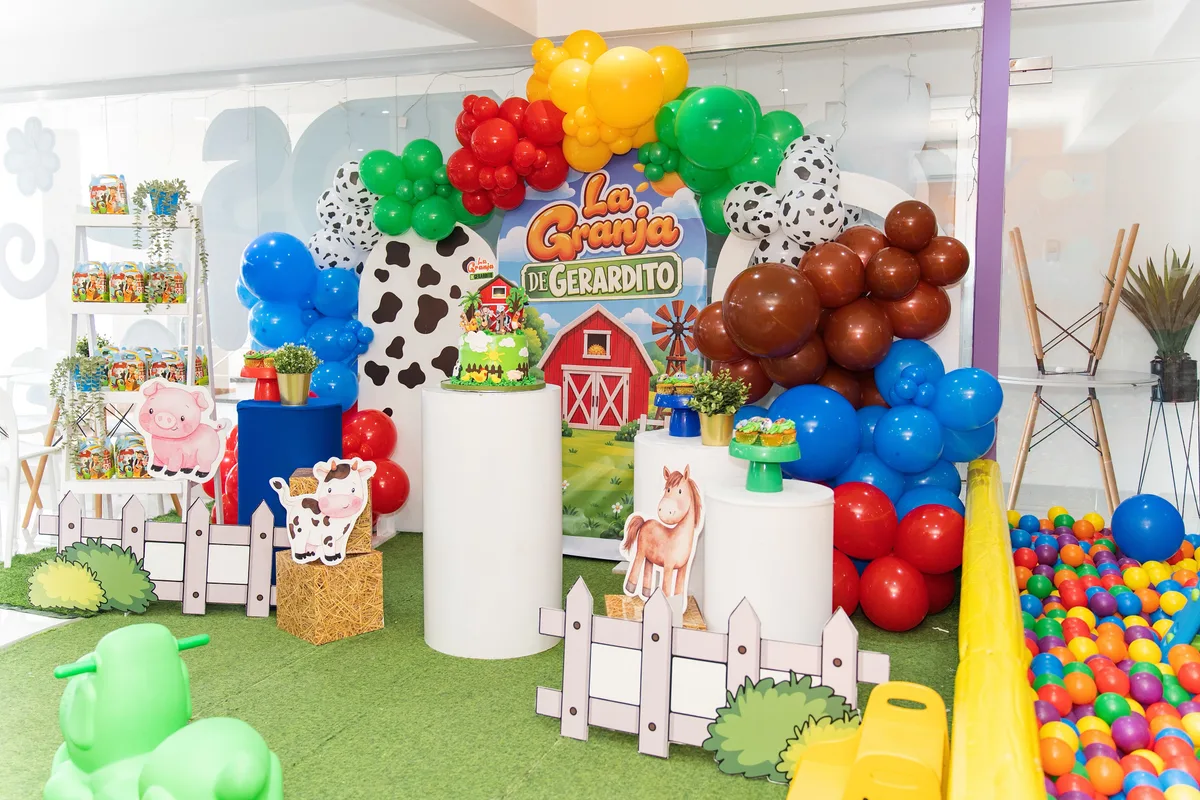Cumpleaños infantil de granja con globos de colores y mesas de dulces