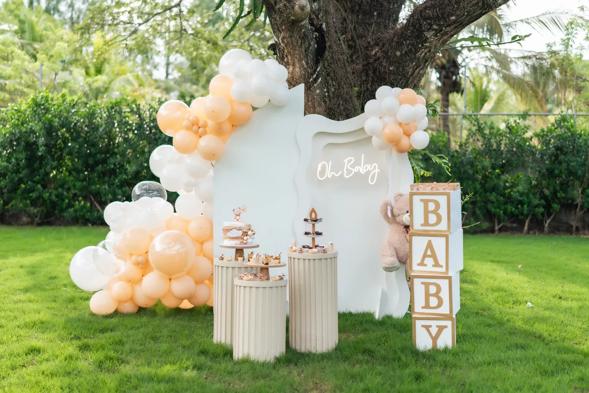 Decoración en un jardín con globos crema y un fondo blanco bajo un árbol